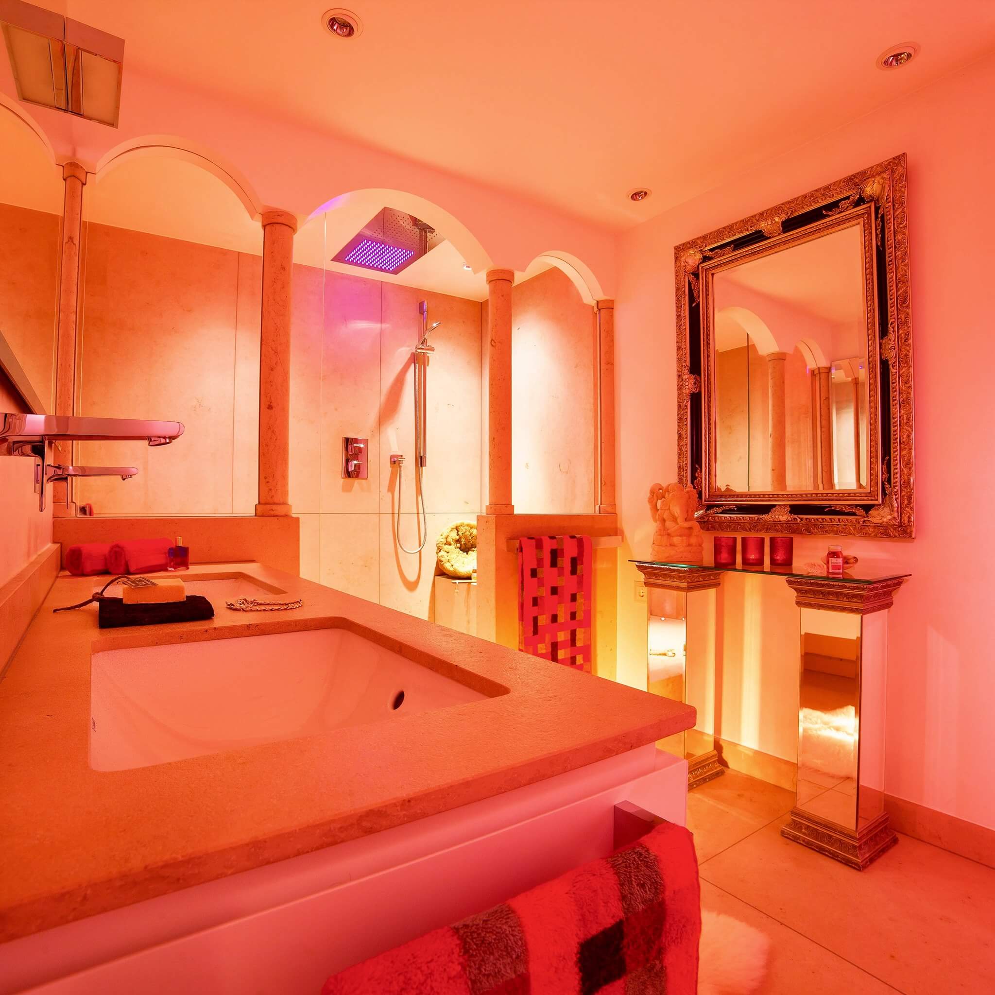 Mediterranes Badezimmer mit Dusche hinter Säulengang in pfirsichfarbener Beleuchtung