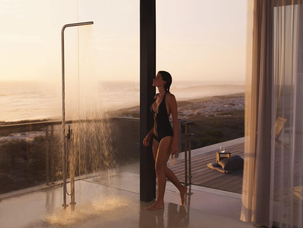 Frau in individuellem Spa mit Dusche und Blick auf Landschaft im Hintergrund