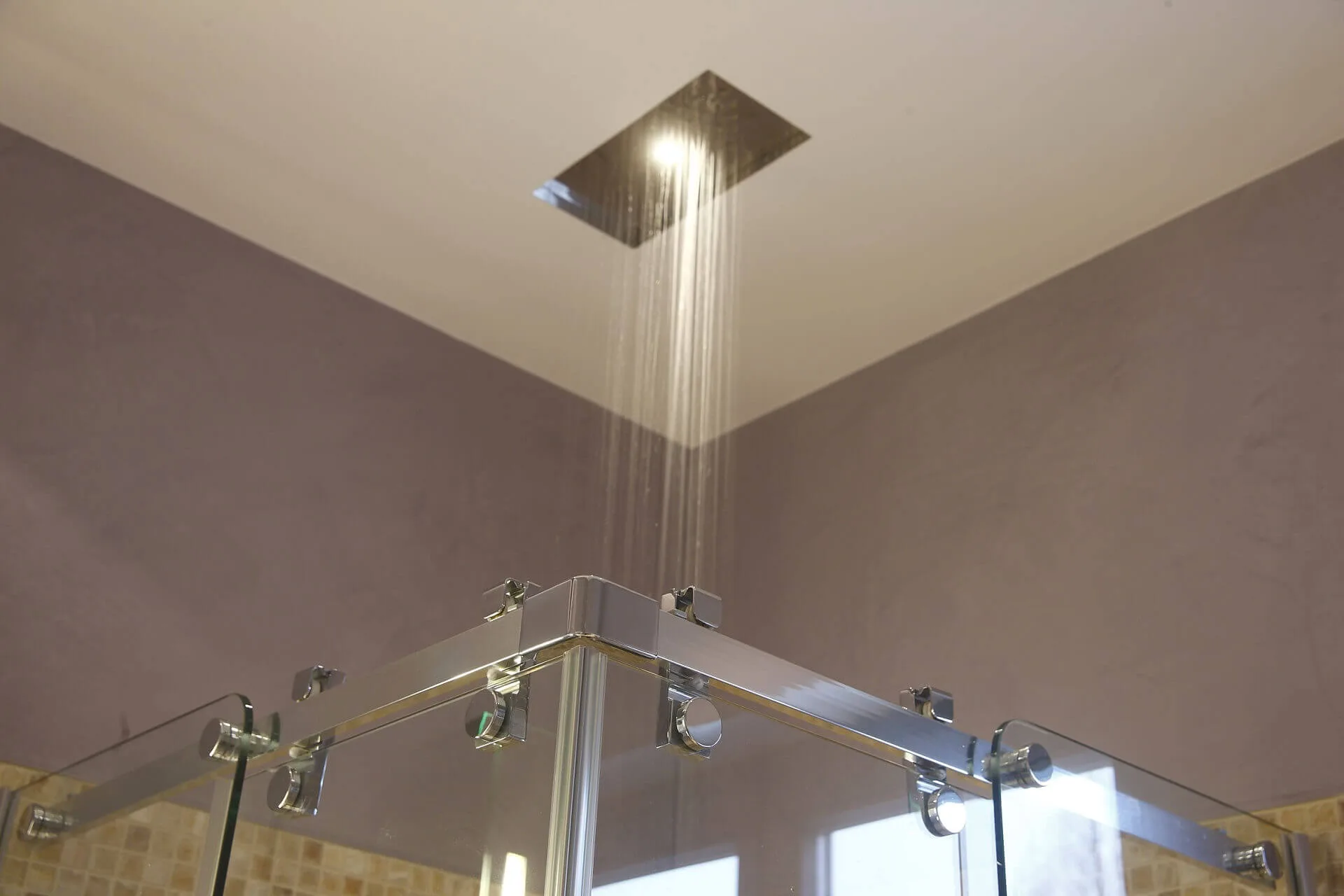 Laufende Regendusche über metallisch eingefasster Duschkabine