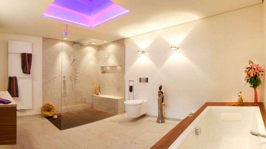 Helles Badezimmer mit afrikanischen Anklängen bei holzverkleideter Wanne und beim Holzboden in Dusche