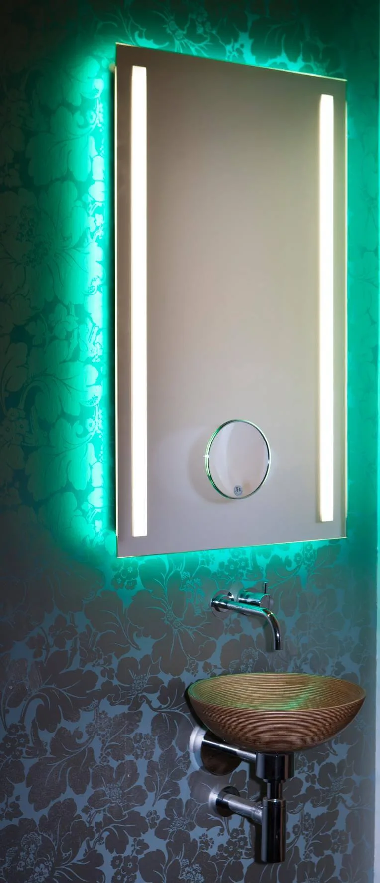 Inmitten der innovativen Einrichtungskonzepte für die gehobene Innenarchitektur sind Lichtspiegel mit farblichem Wechsel das revolutionäre Highlight. In einer einzigartigen Kombination aus technischem Raffinesse, Funktionalität und anspruchsvollem Design definiert Torsten Müller das Thema Lichtdesign-Spiegel neu. Der Schöner Wohnen Profi weiß, Licht und Farbe tragen wesentlich dazu bei, das Raumgefühl angenehm zu beeinflussen. In formaler Reduziertheit fokussiert der farbliche Lichtspiegel den Blick auf sich. Auffällig ist das intelligente indirekte Beleuchtungskonzept, das stets für die individuelle Lebensfreude justierbar und bedienbar ist. Hochwertig und äußerst funktional ist auch die geeignete Bedienbarkeit für jede Generation von IPhone- und IPad-Geräten per IPhone App und durch die Einbindung in die Smart Home Technik somit auch der fortschreitenden Digitalisierung im Badezimmer angepasst. Individualität pur in unterschiedlichen Spiegel-Formaten, Beleuchtungsarten oder mit integriertem Kosmetikspiegel (mit 5- facher Vergrößerung ein perfekter Assistent bei der Rasur oder beim Schminken) sind realisierbar inkl. optimaler Gesichtsausleuchtung. Die LED-Lichtkomposition ist langlebig, der Stromverbrauch minimal. Der Lichtfarbenspiegel by Torsten Müller ist erhältlich in den vielfältigsten Größen und somit passend im Bad, Spa und Raumdesign und natürlich auch im Gäste WC einzusetzen. 