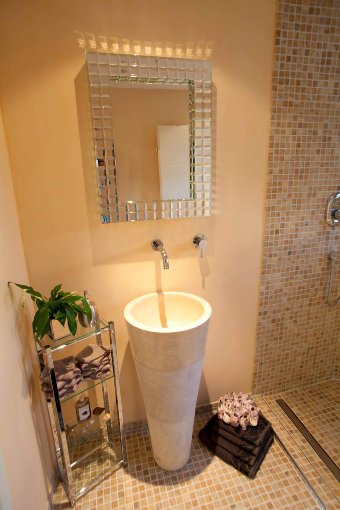 Mediterranes Gäste WC Design in hellen Tönen mit Natursteinwaschtonne und Mosaikboden
