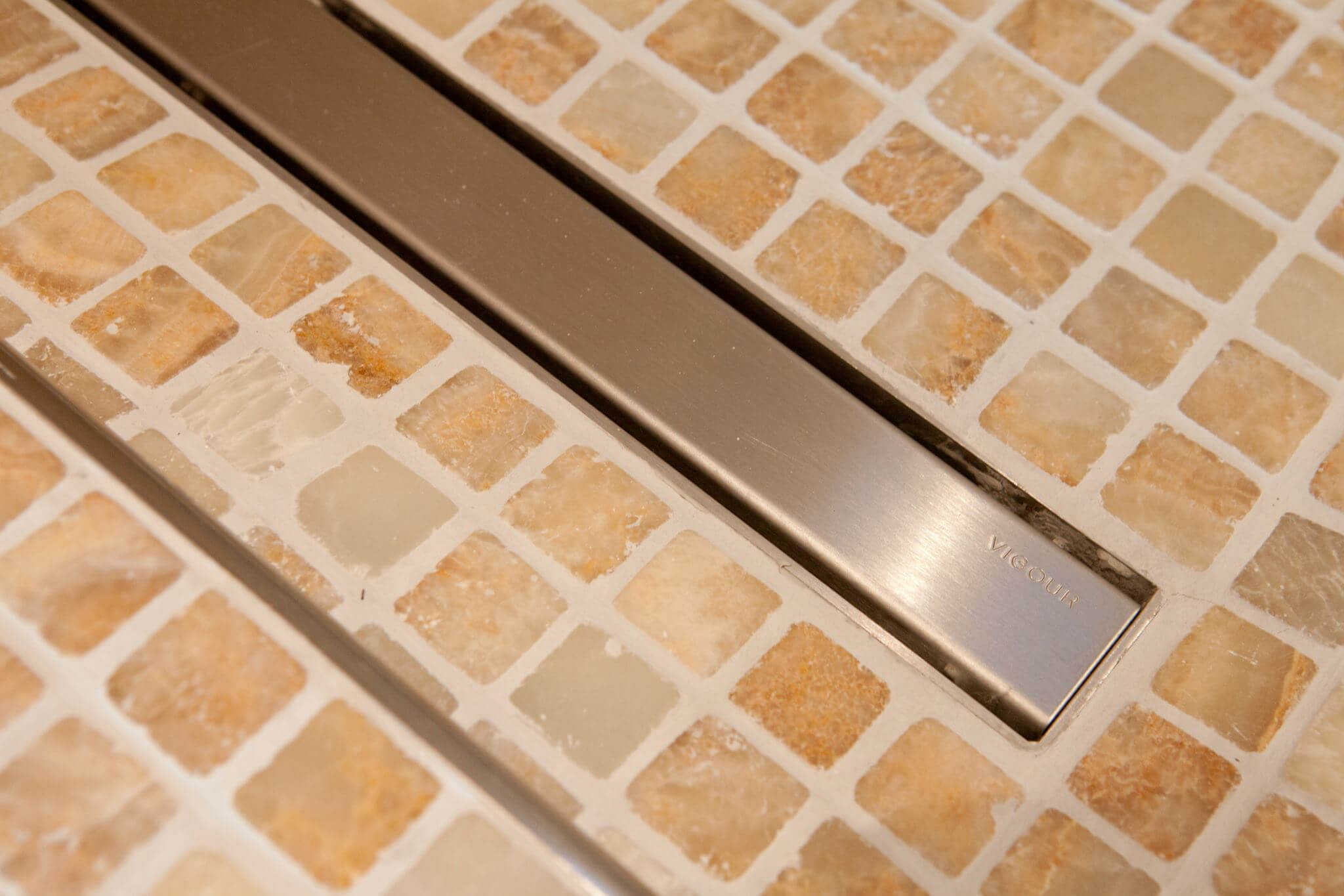 Detailansicht der Abflussrinnen im beigefarbenen Mosaikboden