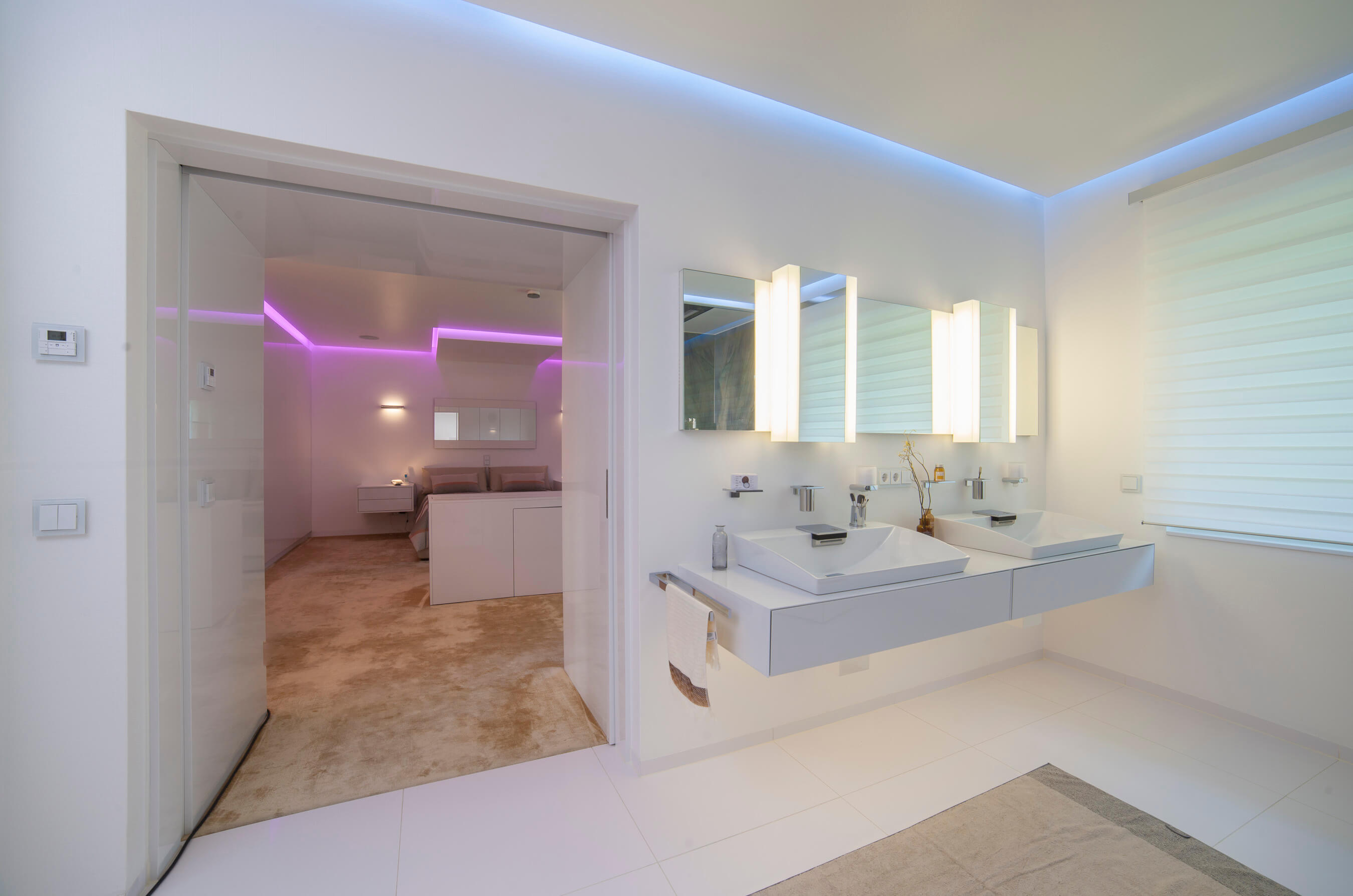 Luxus Badezimmer mit weißem Waschbereich und Tür mit Blick ins Schlafzimmer