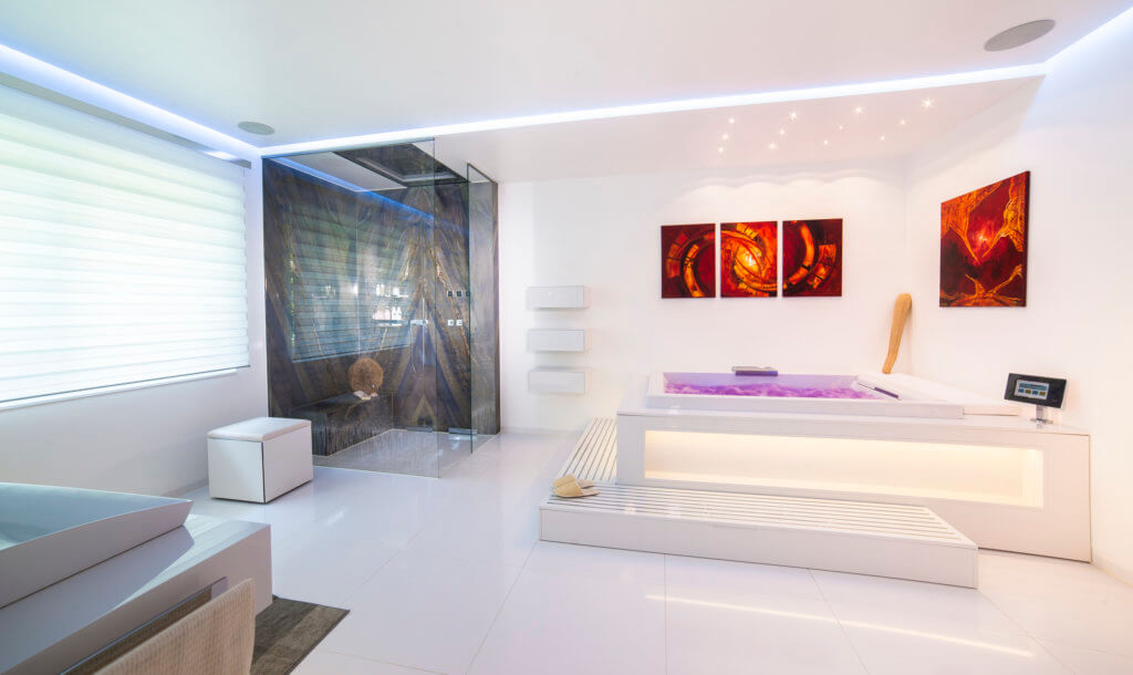Luxus Badezimmer mit Natursteindusche und beleuchteter Badewanne sowie Bildern an der Wand