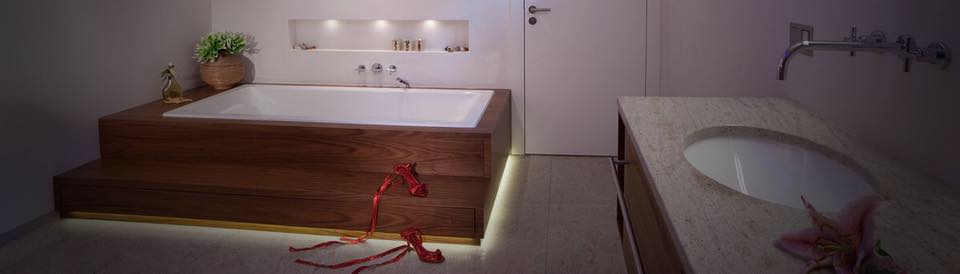 Perfekter Ort für ein Milch Honig Bad: Badewanne mit Holzrahmen und beleuchteter Nische darüber