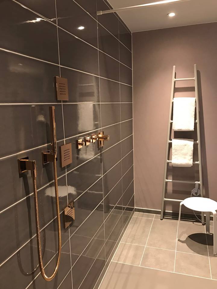 Dusche mit leiterförmigem Tubes Heizkörper Dusche mit kupferfarbiger Armatur und leiterförmigem weißen Tubes Heizkörper