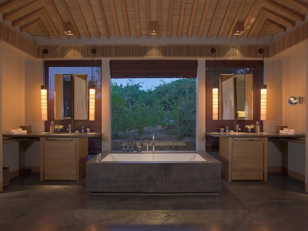 Rechteckige Luxus Badewanne zwischen zwei Waschplätzen mit offener Holzdeckenkonstruktion und Blick nach draußen