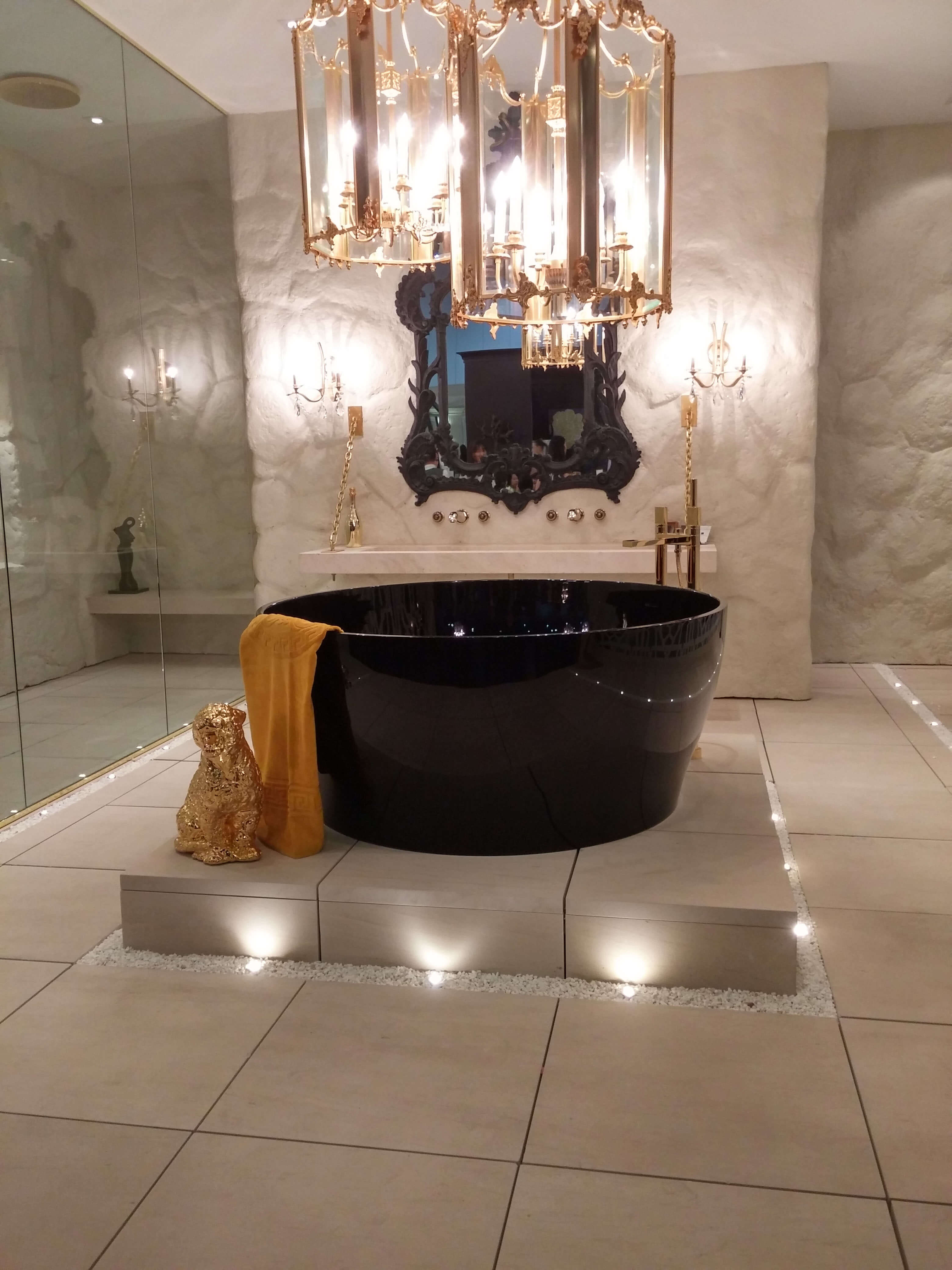 Runde Luxus Badewanne in glänzendem Schwarz unter einem modernen Kronleuchter