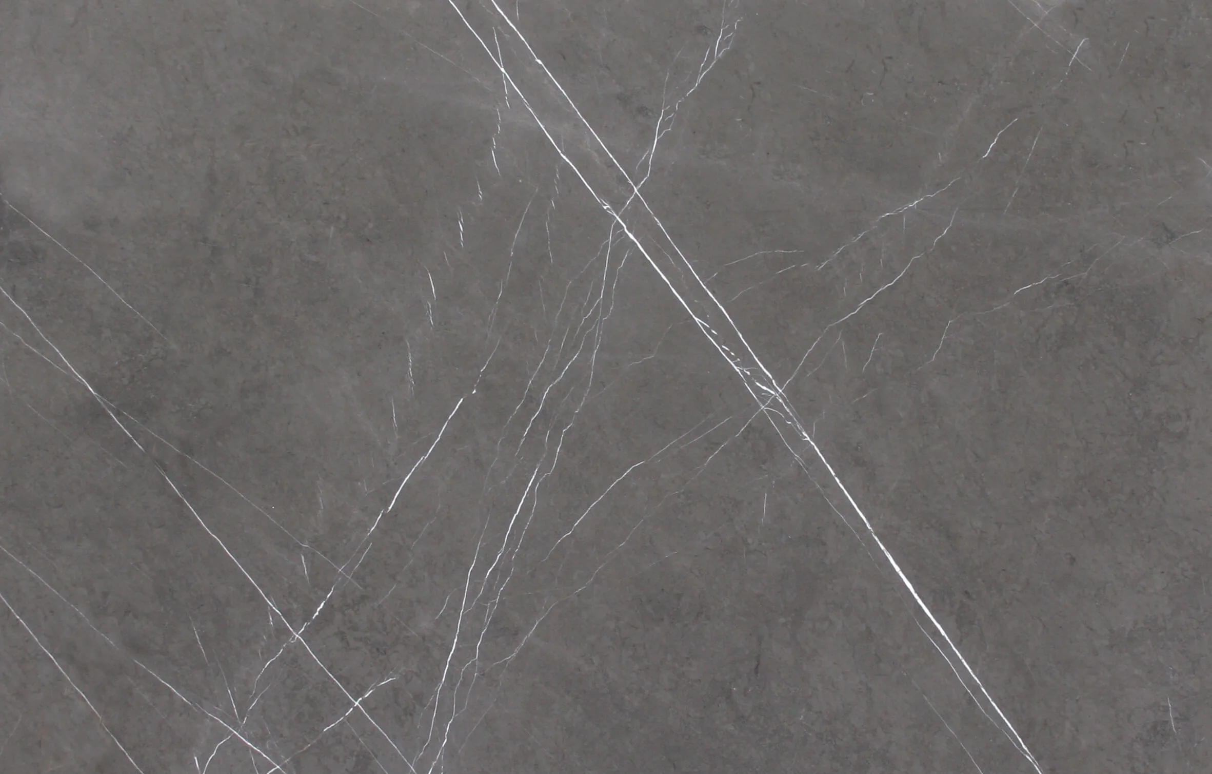 Gray Stone fängt die Essenz von Grau ein, die Farbe, die das Konzept der Eleganz am besten zum Ausdruck bringt. Die endlosen Nuancen dieser Nuance sind in einem außergewöhnlichen Material zusammengefasst. Anthrazit, Taubengrau, Esche und Taupe scheinen in einem ansprechenden Gemälde zu schmelzen und neu zusammenzusetzen, eine kostbare Leinwand, auf der die Natur feine weiße Adern, kreative und unerwartete Akzente, die von einer zeitlosen Schöpfungskraft ausgehen, entworfen hat: Die Erde. Gray Stone ist ein raffiniertes Zeichen der Natur im Design und eine ideale Lösung für das Entwerfen und Durchführen von Qualitätsverkleidungen oder großartigen Arbeitsplatten. Verfeinerung und Innovation für Küchenräume mit imposanten skulpturalen Dimensionen Auf der IMM 2019 präsentiert Antolini ein beeindruckendes Display, das die Ausdrucksintensität von Naturstein steigert und sich gleichzeitig auf innovative Technologien konzentriert. Antolini, führend in der Herstellung von Naturstein und an der absoluten Spitze der Branche, nimmt an der IMM Cologne mit einer hoch entwickelten Installation des Designers Alessandro La Spada teil. Das harmonische und elegante Ausstellungsdisplay umfasst zwei Küchenblöcke, einer aus Bronze Amani und der andere aus Gray Stone: Wenn das erste Material mit seinen warmen, weichen, zarten Beige- und Cappuccino-Tönen fasziniert, die mit dunkleren Adern durchdrungen werden, überrascht das zweite Material durch seine flüchtige Persönlichkeit die verschiedene Grautöne mit schwer fassbaren weißen Adern abwechselt und ein abstraktes Design präsentiert, das so einzigartig ist, wie es nur die Natur bieten kann. Beide Küchenblöcke zeichnen sich durch eine lineare und geometrische Eleganz aus und verfügen über eine Schiebebrücke, die ihre Oberfläche verdoppelt und eine weitere verdeckte Oberfläche auf magische Weise enthüllt. Das Material von Amani Bronze und Grey Stone, das für die auf der IMM gezeigten Küchen verwendet wurde, wurde mit Azerocare behandelt. Azerocare wurde von Antolini patentiert und wurde speziell für Marmor, Onyx und weiche Quarzite entwickelt. Es handelt sich um eine revolutionäre Behandlung, die maximalen Schutz gegen Flecken und Ätzen durch Kontakt mit Nahrungsmitteln und sauren Substanzen garantiert. Azerocare wird von Antolini direkt auf die Plattenoberflächen aufgetragen und ist eine Garantie gegen mögliche Schäden, die durch die Verwendung von Produkten wie Wein, Kaffee, Öl, Essig, Tomatensauce und Fruchtsäften entstehen können, und ist daher die ideale Lösung für Oberflächen in Küchenumgebungen . Der elegante, graue Steinboden (Leder) vervollständigt das Gesamtbild und gibt der Installation ein Gefühl von Einheit. Über den Küchenblöcken ragen zwei lange Deckenleuchten mit Bronze- und gebürstetem Stahlüberzug hervor. Dahinter und auf einer Seite befinden sich die majestätischen und markanten Wände aus Gray Stone I Stratos Design und Bronze Amani I Stratos Design, die zart von geräucherten Spiegeln unterbrochen werden, die die Pracht des Steins mit überraschendem Stil widerspiegeln.