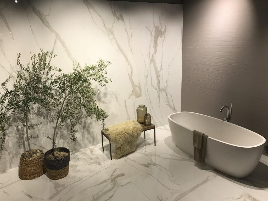 Freistehende Badewanne mit Sitzgelegenheit, Pflanzen und Marmorwand