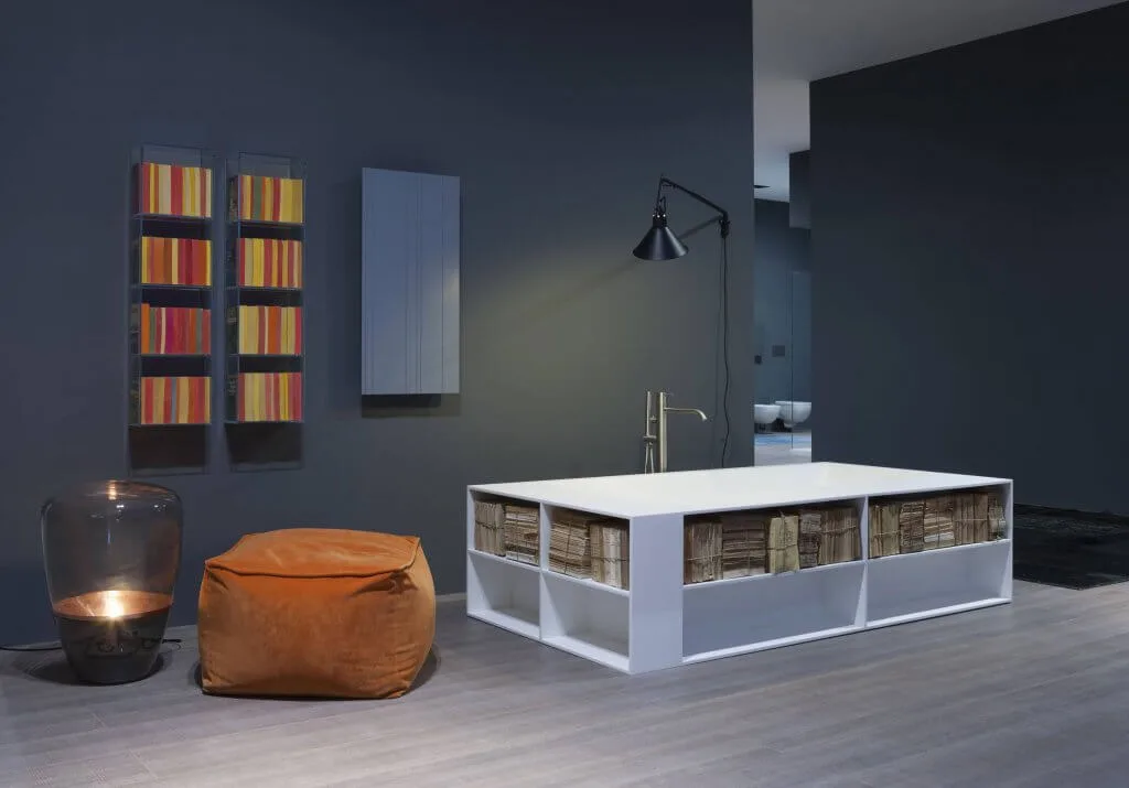 Freistehende Wanne mit seitlichen Ablageflächen neben einem Sitzsack und zwei Bücherregalen