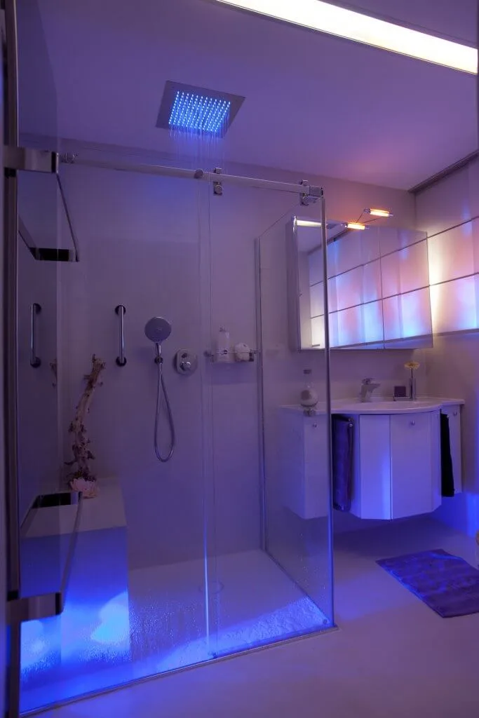 Moderne Dusche mit Sitzbank und blauer Beleuchtung