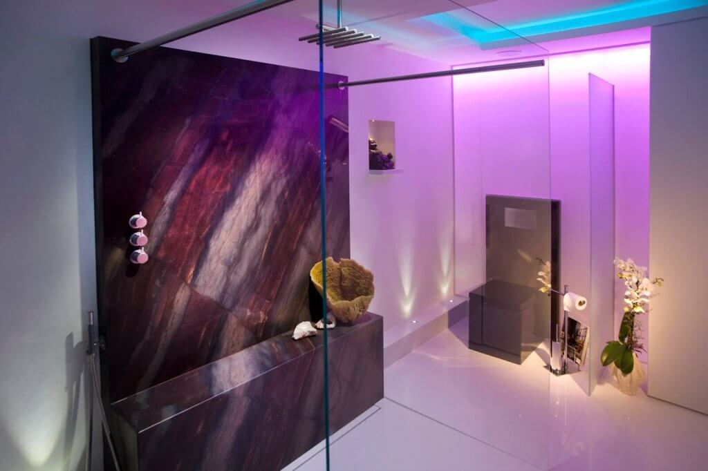 Moderne Dusche mit Natursteinwand und -sitzbank hinter Glaswand