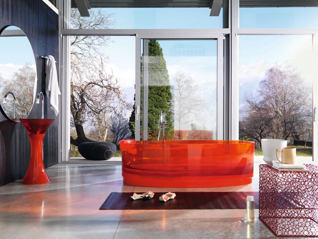 Freistehende Badewanne aus orangem semitransparentem Glas und passender konusförmiger Waschtisch