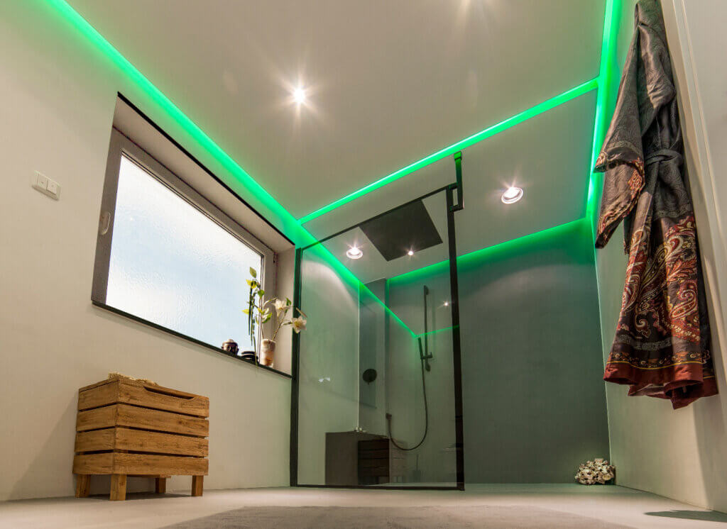 Fugenloses Badezimmer mit grüner Voutenbeleuchtung