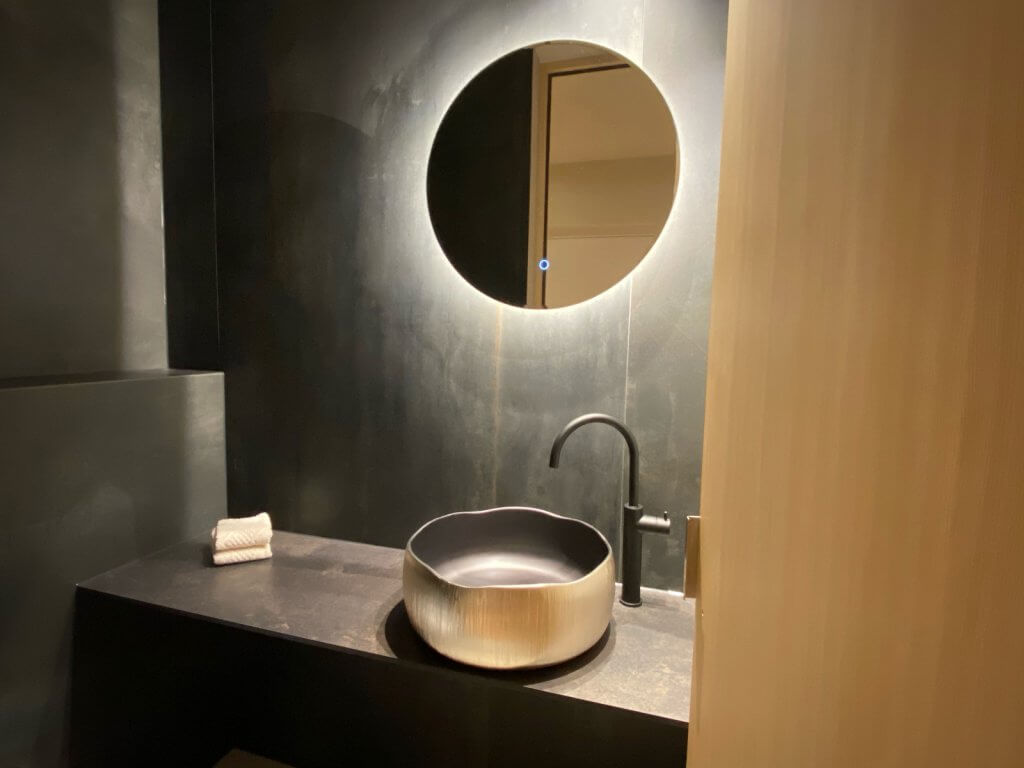 Goldenes, fein strukturiertes Waschbecken von myglassdesign mit rundem Spiegel