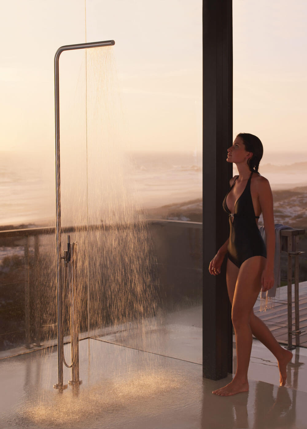 Frau unter Vola Luxusdusche FS3 in grossem Badezimmer mit Panoramafenster
