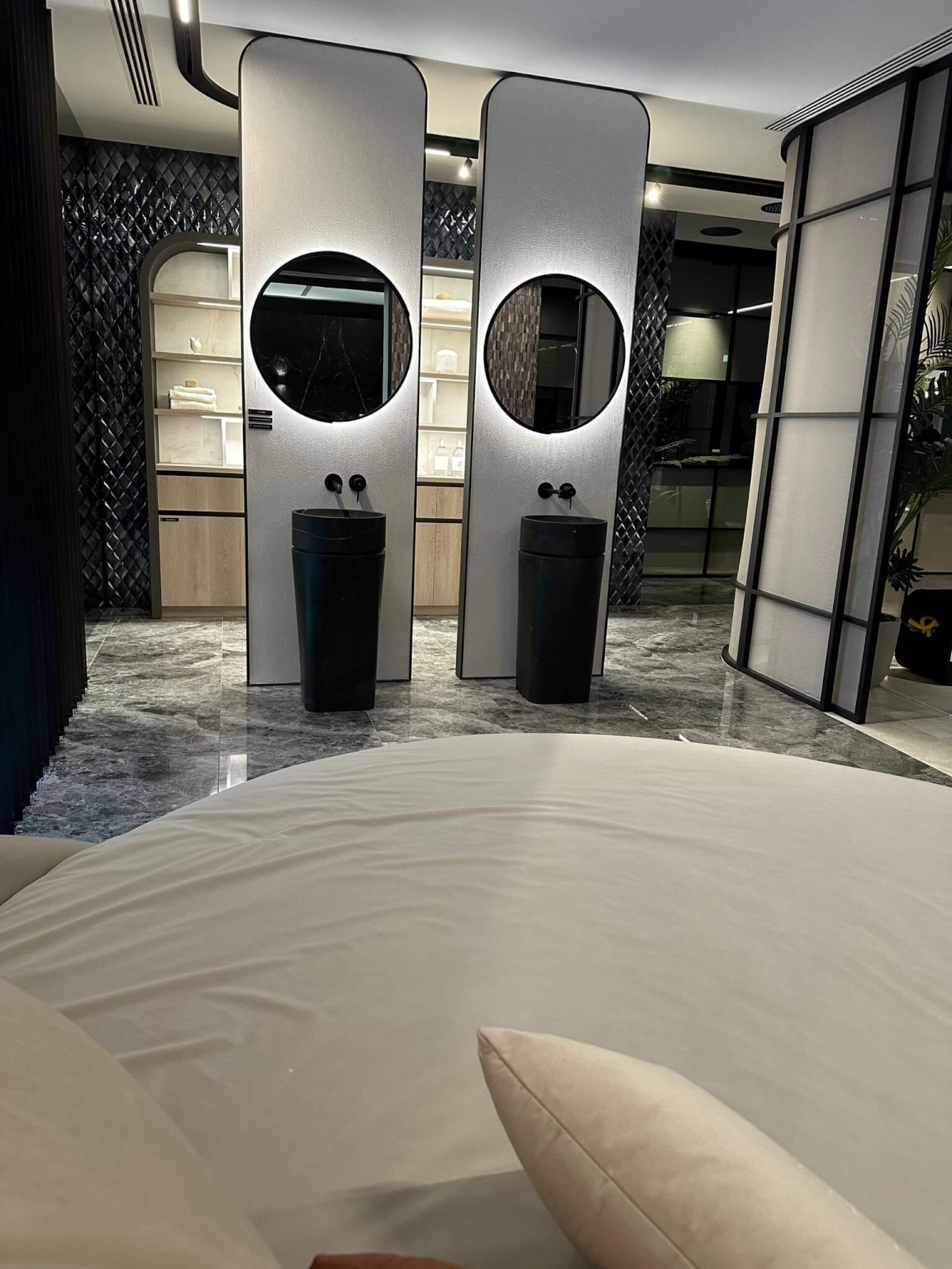 En-suite-Bad von Porcelanosa mit zwei schwarzen Waschtonnen und runden Spiegeln