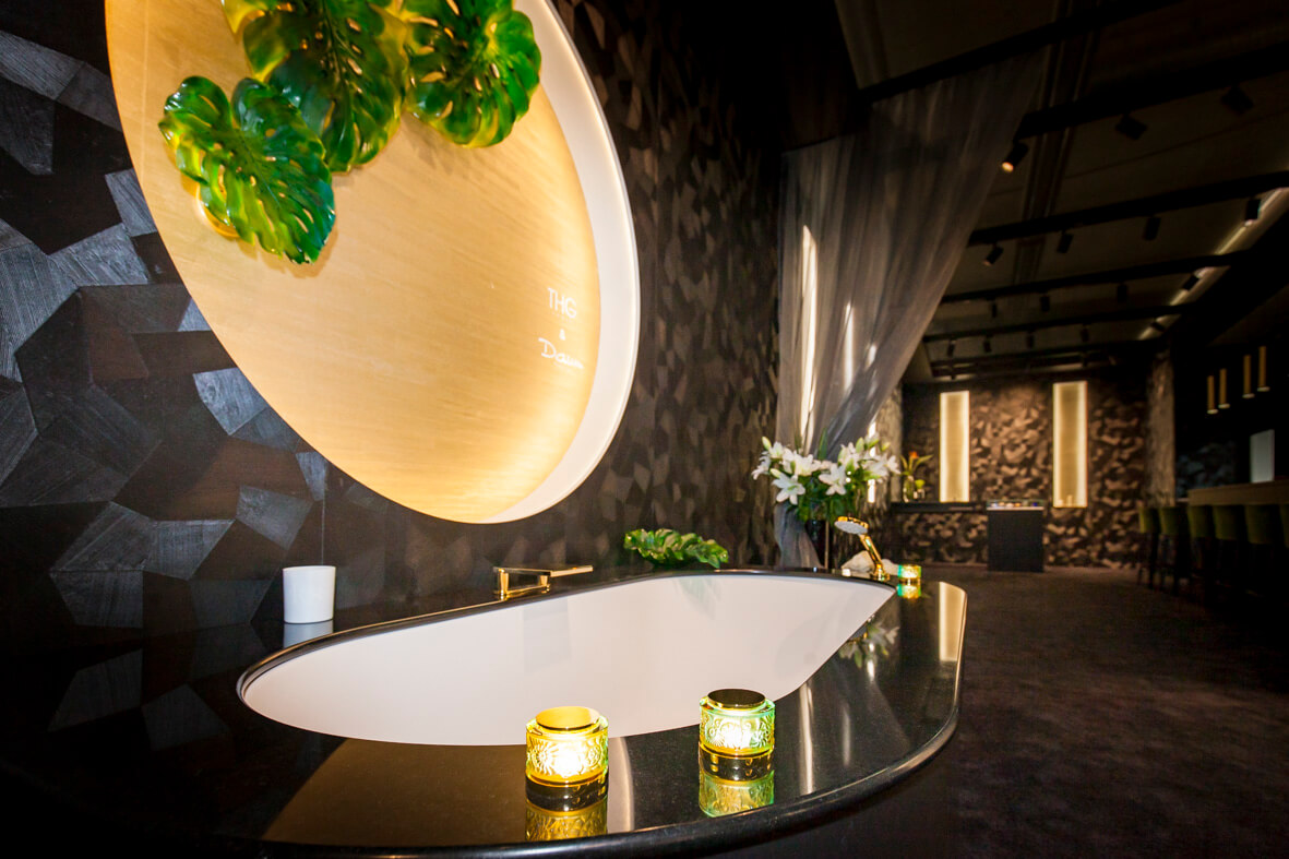 Weisse Badewanne mit dunkelem Naturstein und bunter Glasarmatur von THG Paris