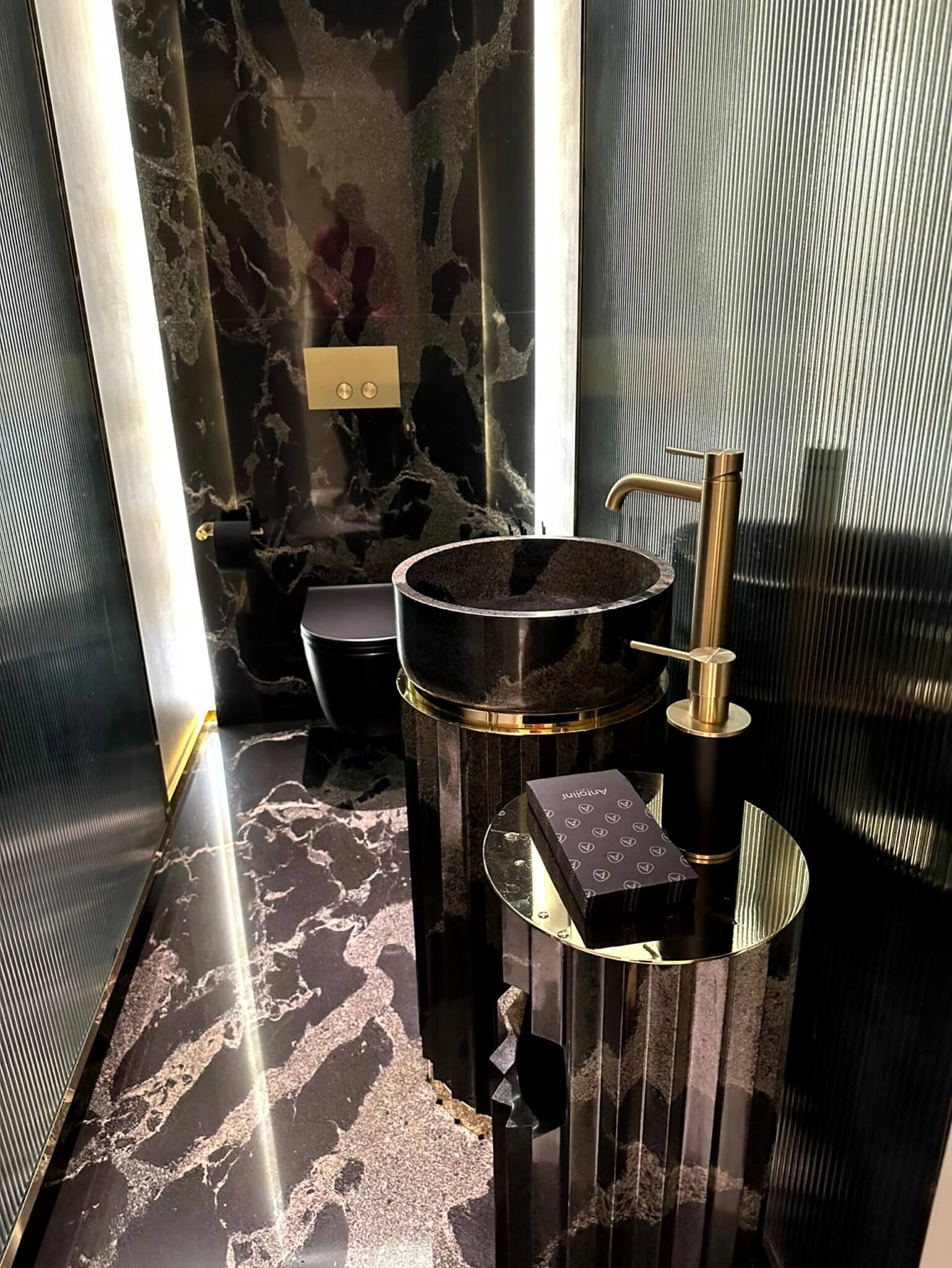 Luxuriöses Gäste-WC mit Naturstein und Messing als Beispiel hochwertiger Badplanung