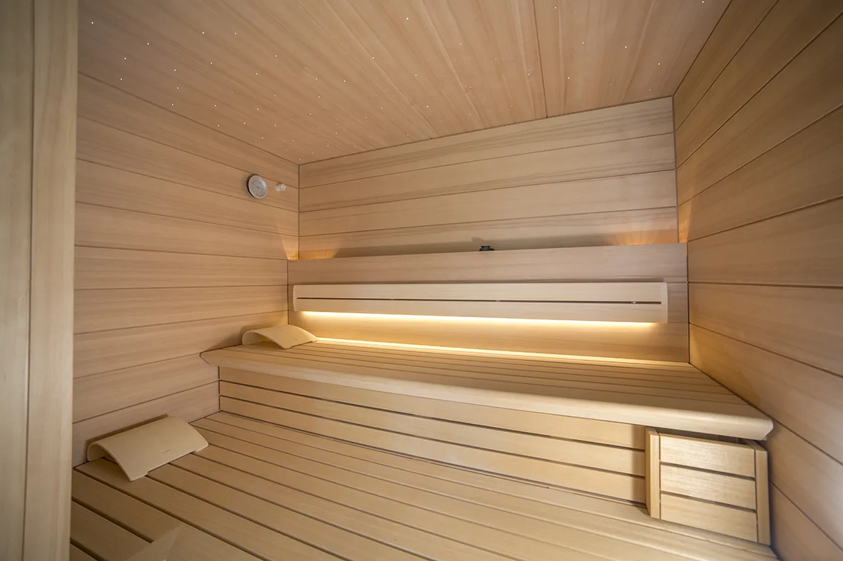 Blick in eine Klafs Sauna mit zwei Ebenen der Liegefläche, Sternenhimmel und sanfter indirekter Beleuchtung.
