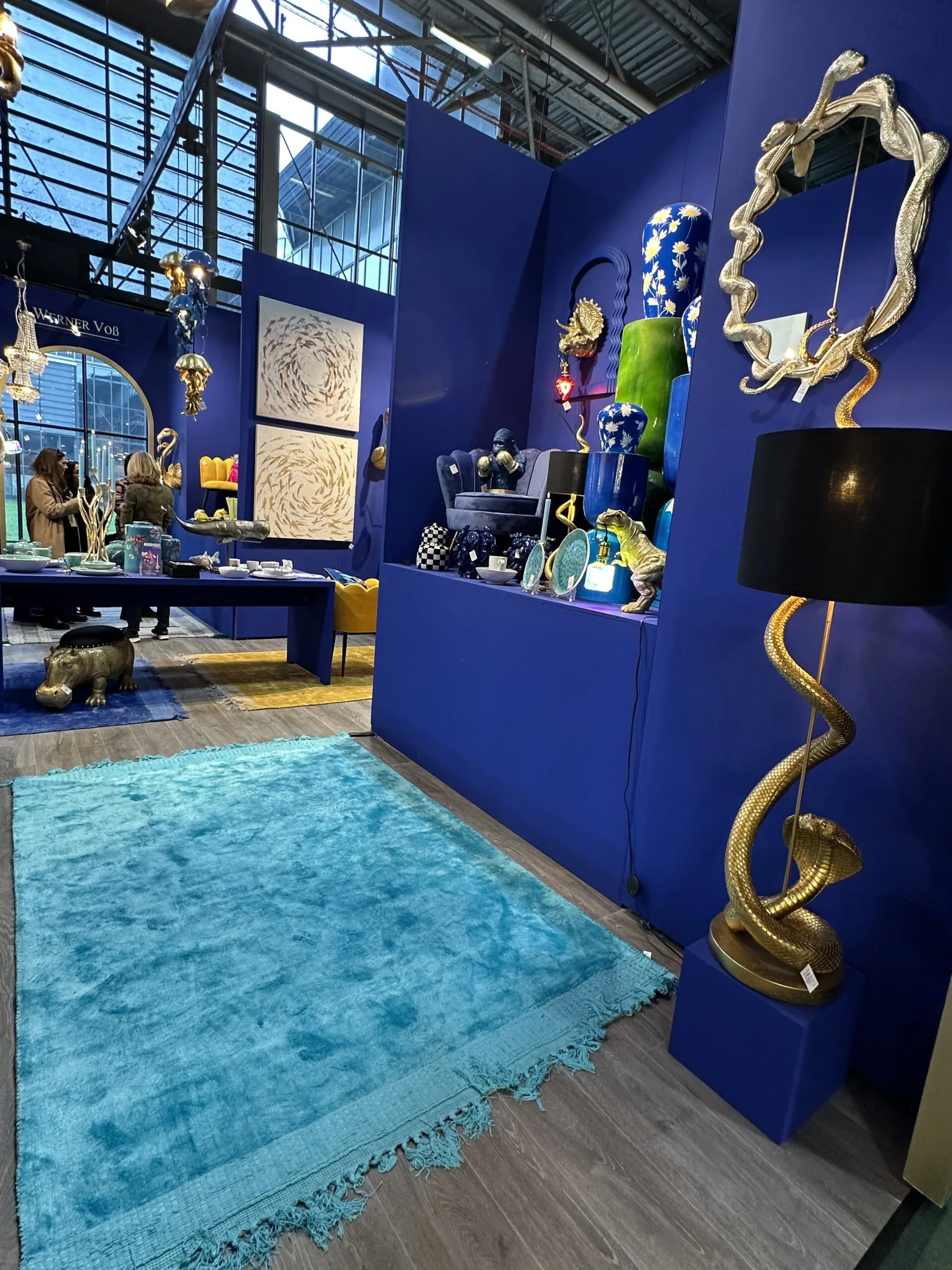 Elegante Ausstellung auf der Maison & Objet 2025 mit blauem Teppich, goldener Schlangenlampe und kunstvollen Dekorationen.
