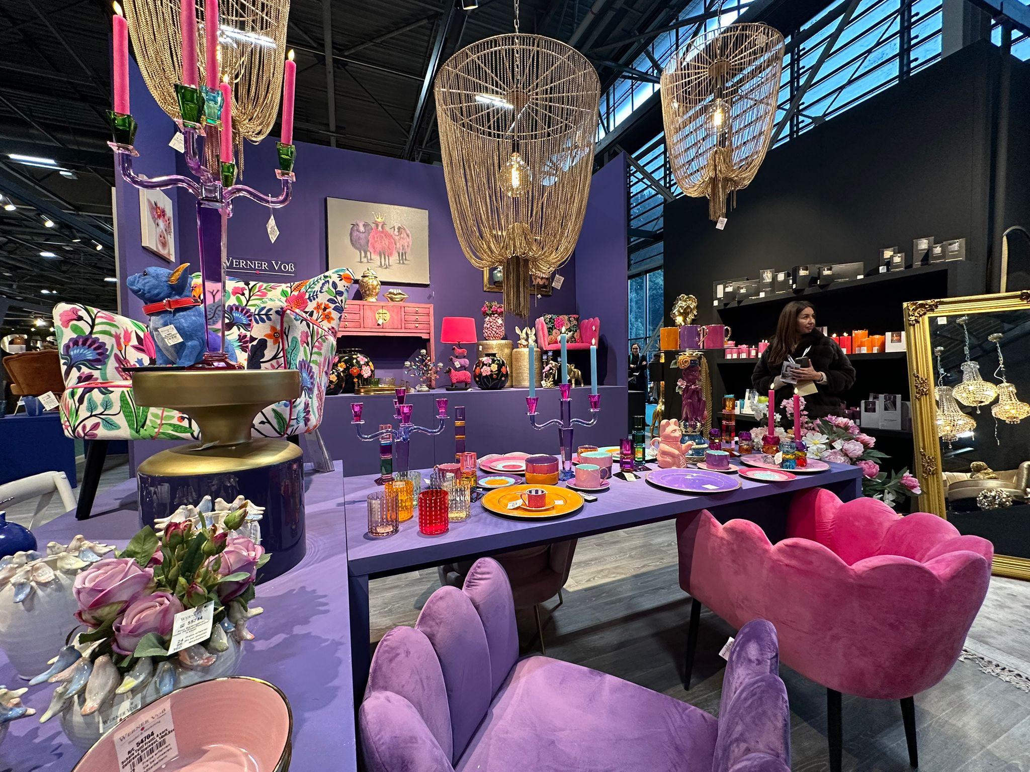 Farbenfrohe Tischdekoration mit rosa Kerzenständern, bunten Tellern und Designerstühlen, präsentiert auf der Maison & Objet 2025.