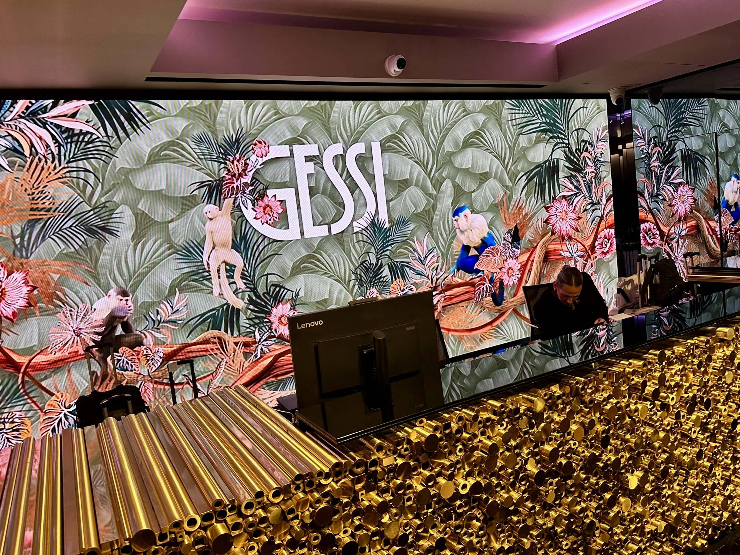 Empfangsbereich im Casa Gessi Showroom mit goldener Armaturenwand und LED-Wand mit tropischem Designmotiv