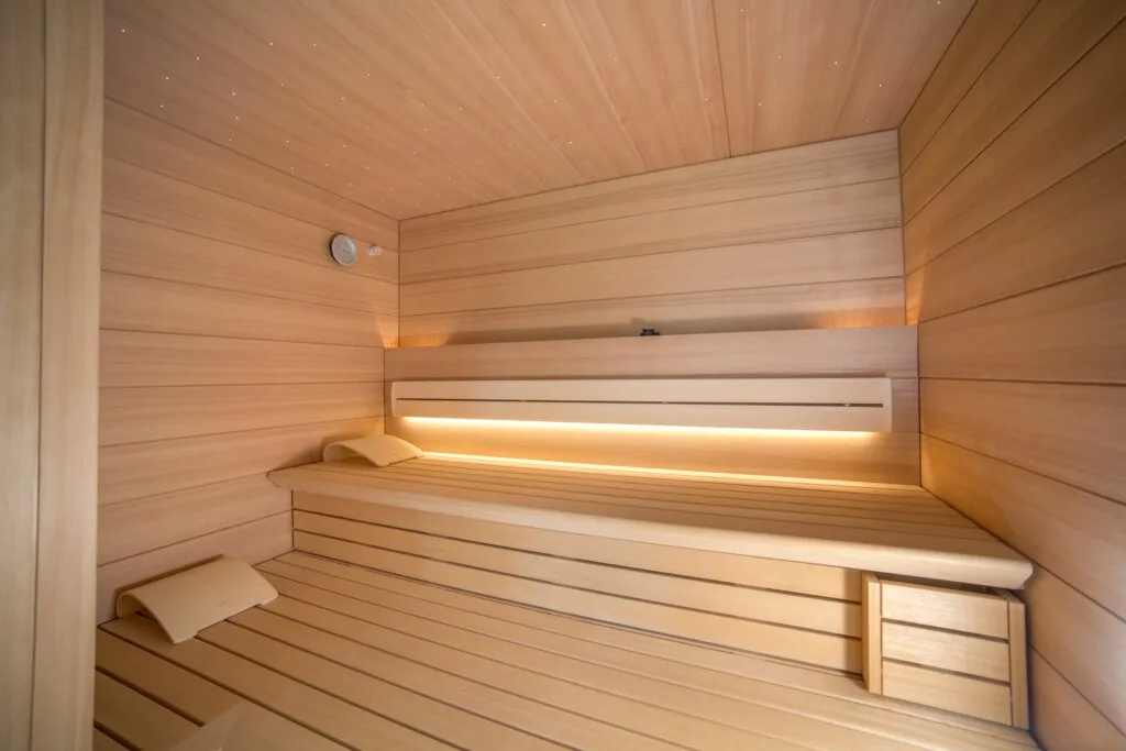 Sauna von Klafs mit zwei Liegeebenen. Bad und Private Spa mit rosa Naturstein, Design by Torsten Müller