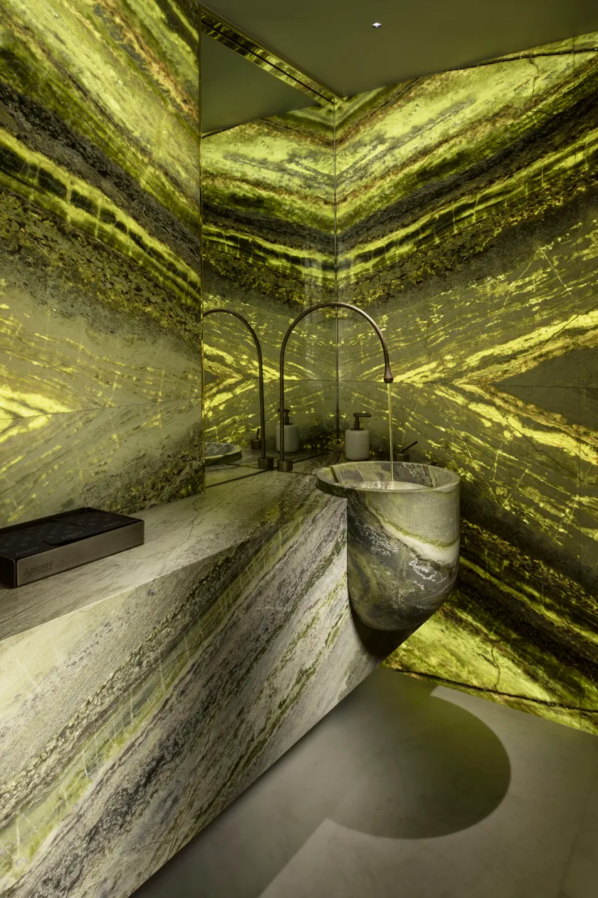 Luxuriöses Badezimmer mit hinterleuchtetem Naturstein Irish Green von Antolini – einzigartiger Waschtisch, Spiegelwand und grün-goldene Lichtwirkung im Spa-Ambiente