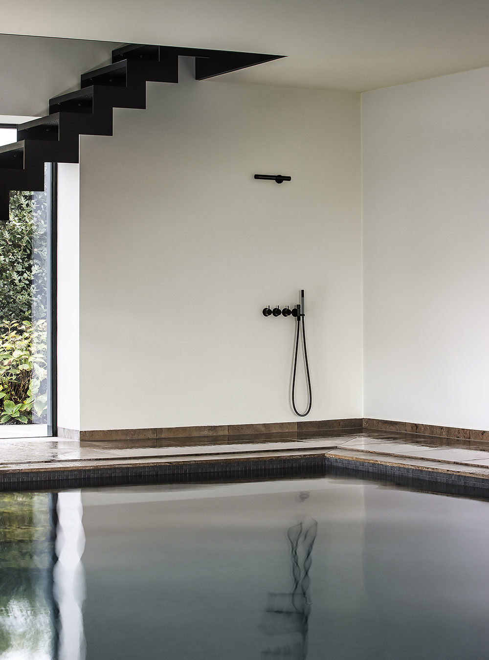 Schwarze VOLA COMBI-33 Duscharmatur an Indoor-Pool mit minimalistischer Architektur