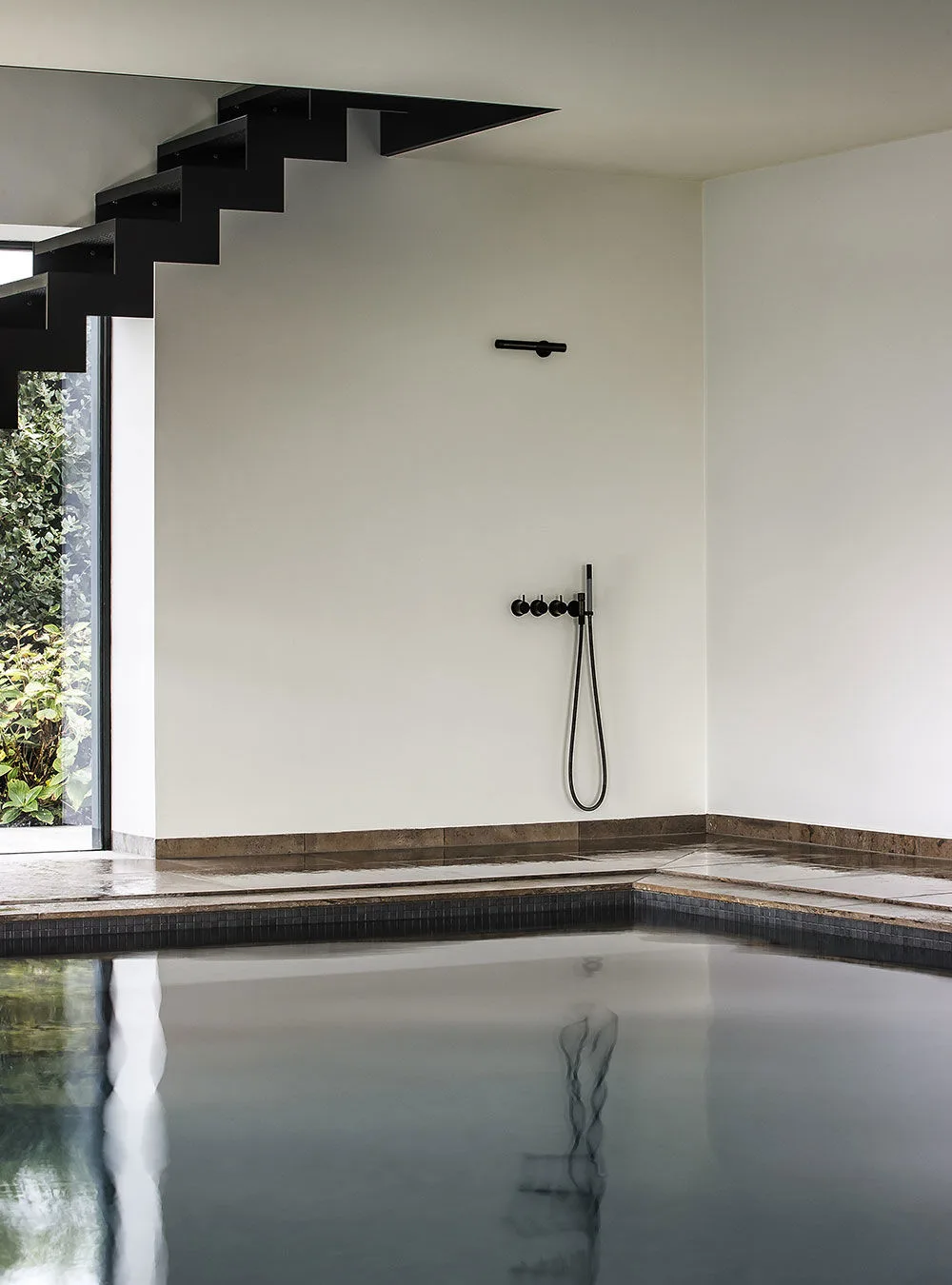 Schwarze VOLA COMBI-33 Duscharmatur an Indoor-Pool mit minimalistischer Architektur