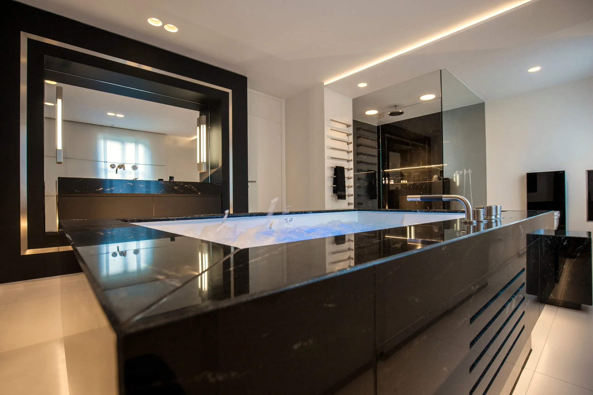 Realisierte Private-Spa-Badarchitektur mit Whirlpool, schwarzem Naturstein, Spiegel und indirekter Beleuchtung