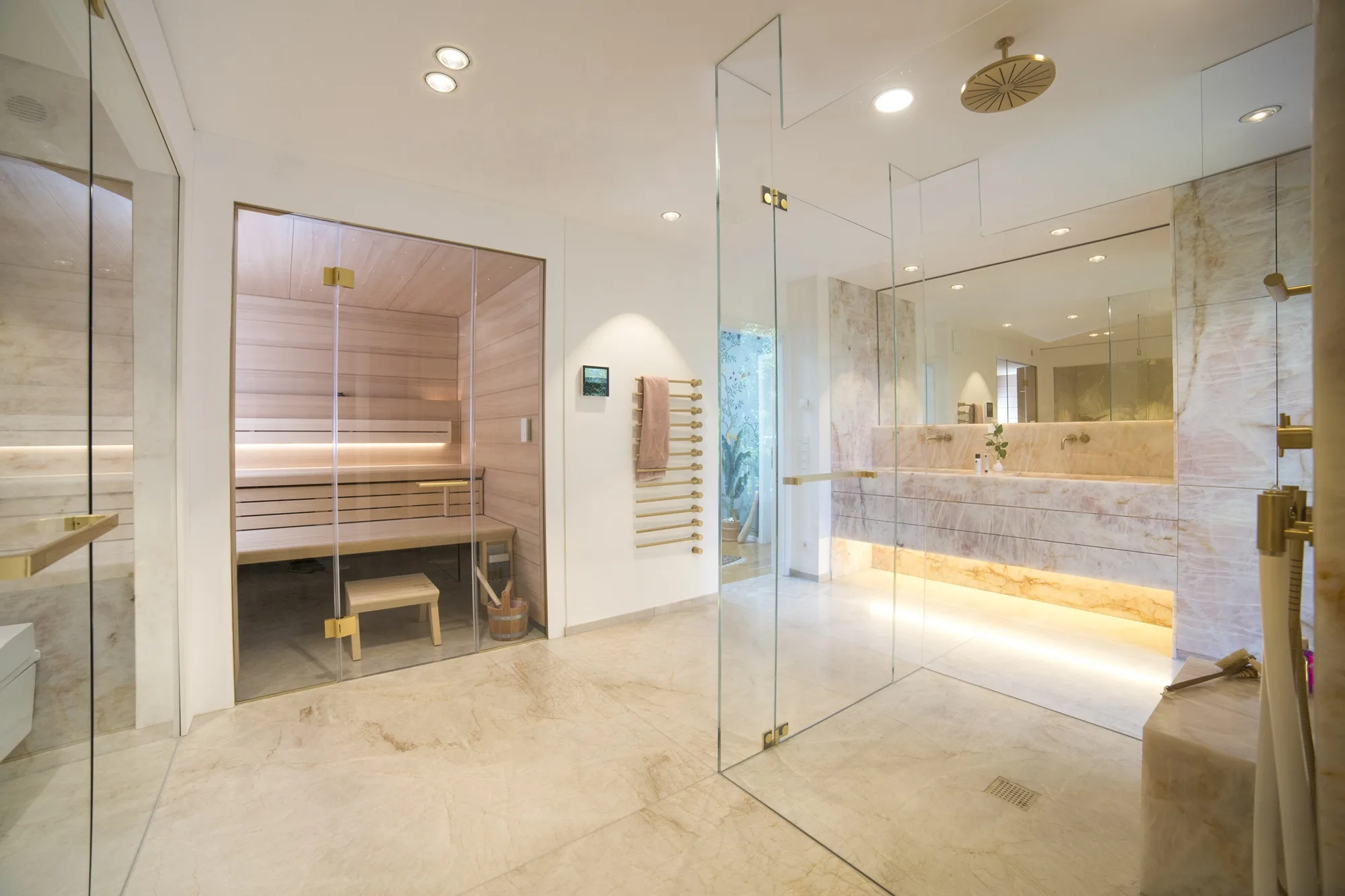 Luxusbad mit integrierter Sauna, Naturstein, freistehender Glasdusche und hochwertiger Lichtplanung