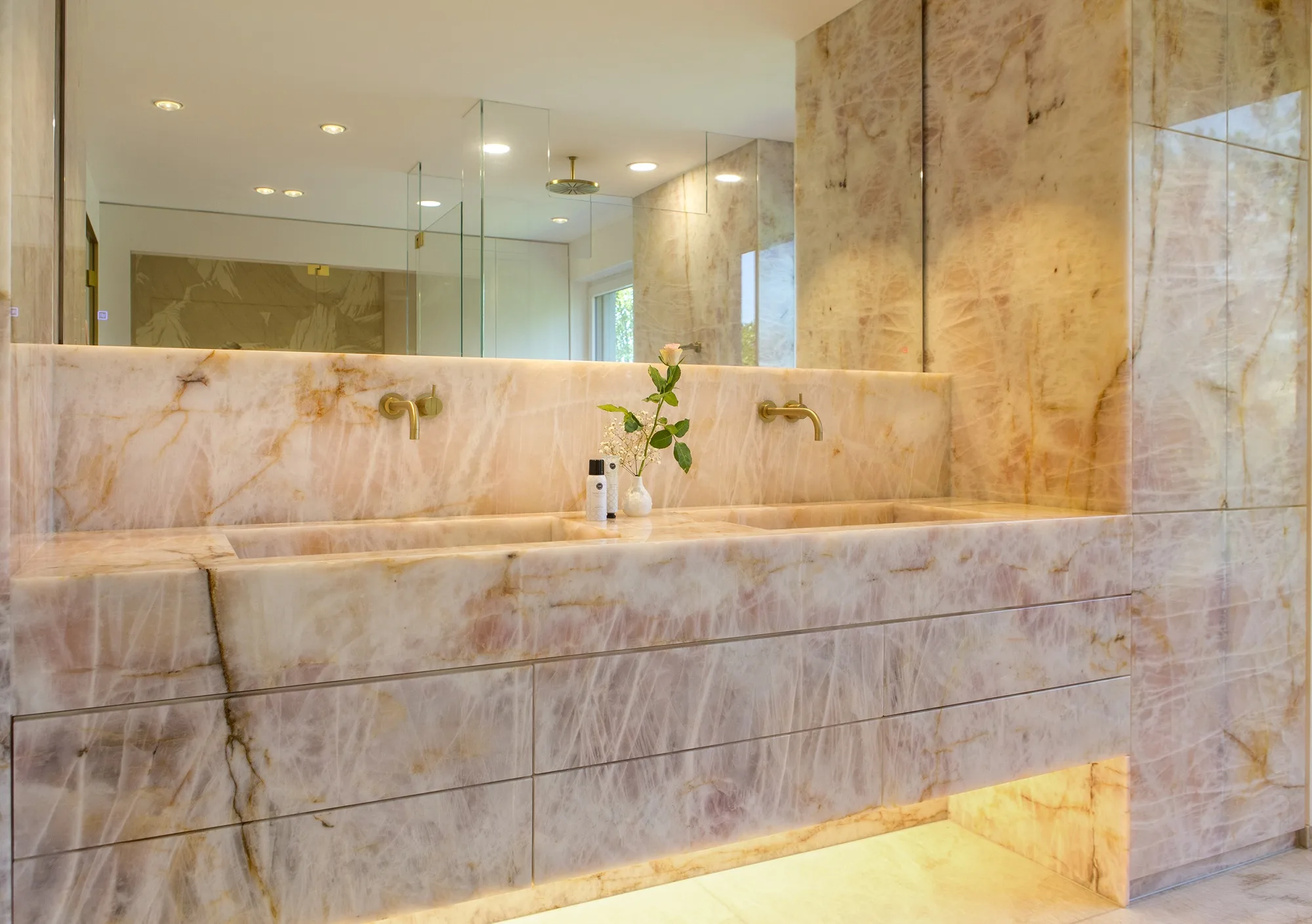 Maßgefertigter Naturstein-Waschtisch aus rosa Quarzit mit indirekter Beleuchtung in einem hochwertigen Luxusbad und Private Spa