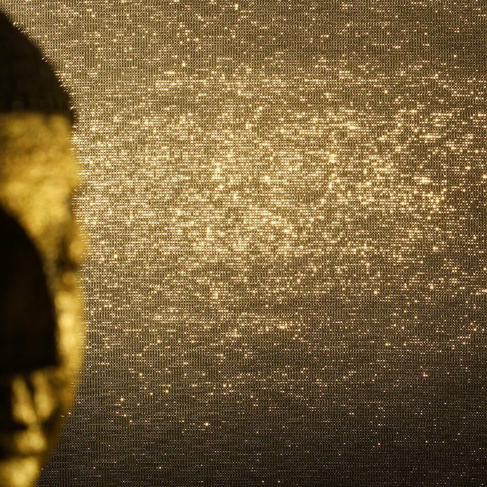 Buddhakopf vor bronzefarbener Mosaikwand