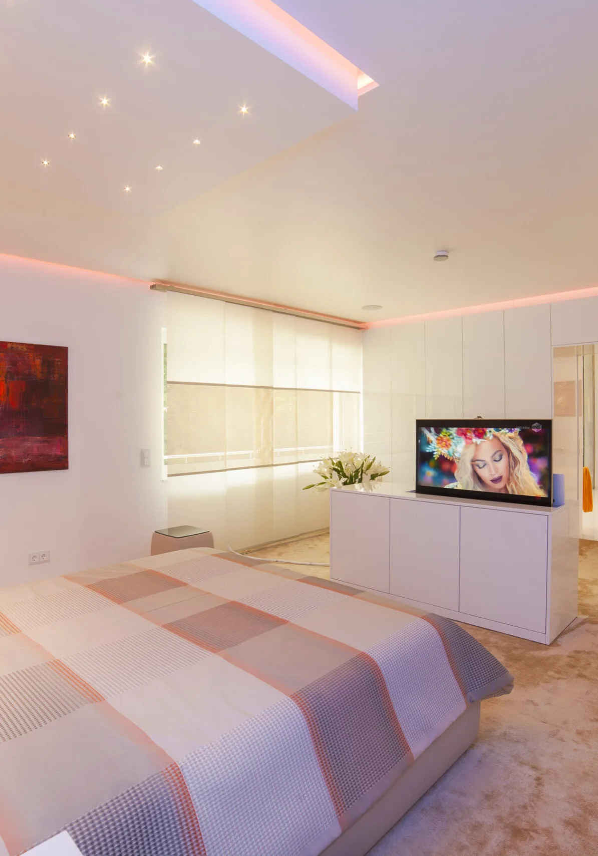 Modernes Designer-Schlafzimmer mit versenkbarem TV, LED-Deckenbeleuchtung und maßgefertigten Einbauschränken.