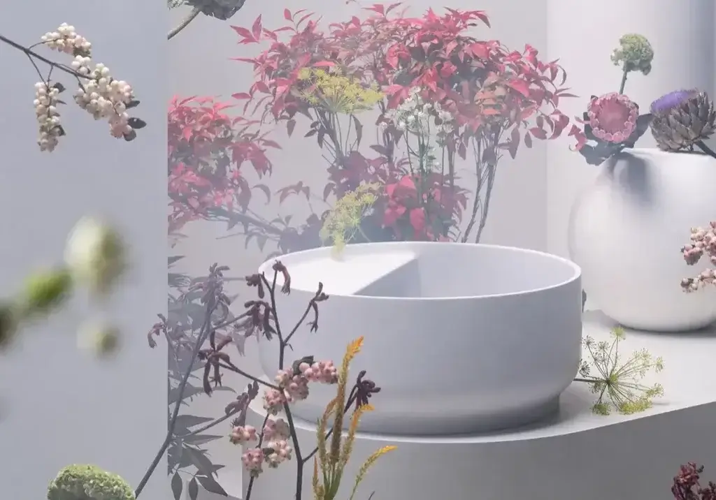 Waschbecken in Weiß vor einem blumigen Pink-Ambiente Salone del Bagno 2024 kos_beam Weißes Waschbecken inmitten eines floralen Ambientes in Pink