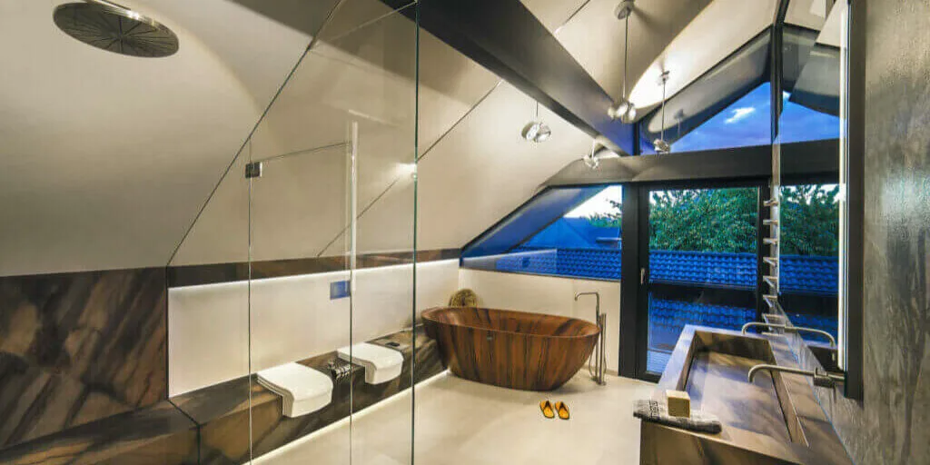 Luxusbad im Dachgeschoss mit freistehender Holzbadewanne, großzügiger Dusche und durchdachter Lichtplanung als Beispiel hochwertiger Badarchitektur